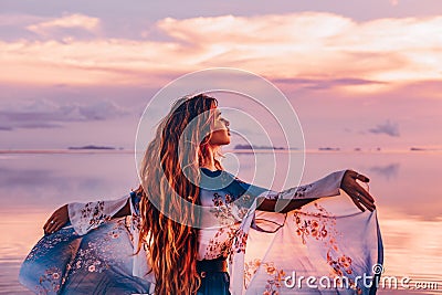 Beautiful young woman in elegant dress on the beach at sunset Stock Photo