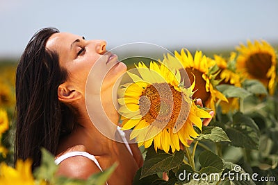 Beautiful young woman feeling the sunflower petals Stock Photo