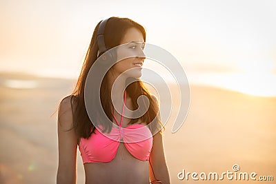 Beautiful young woman in headphones walking on the beach and enjoing of music listening Stock Photo