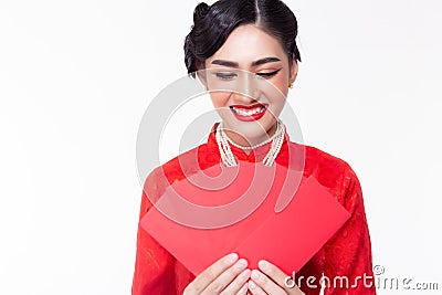 Beautiful young woman holding red envelopes and looking at red envelopes with smiley face in Chinese New Year. Gorgeous woman feel Stock Photo