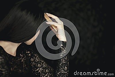 Beautiful young woman holding vintage old book to her face, very dark atmospheric sensual rural studio shot Stock Photo