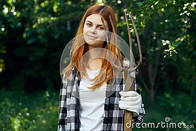 Beautiful young woman holds a fork for working in the garden, summer, gardener Stock Photo