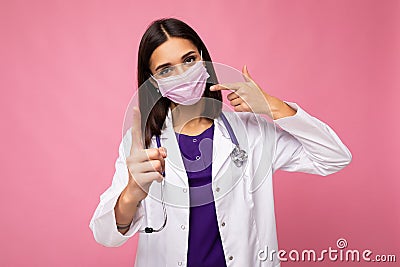 Beautiful young woman holds and wears a white medical mask to protect yourself from corona virus, cares for her health Stock Photo
