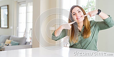 Beautiful young woman at home smiling confident showing and pointing with fingers teeth and mouth Stock Photo
