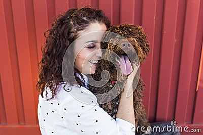 Beautiful young woman hugging her dog, a brown Spanish water dog Stock Photo