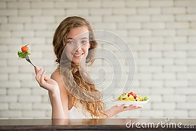 Young woman in joyful postures with salad bowl on the side Stock Photo