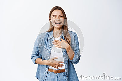 Beautiful young woman laughing and having fun, chuckle while holding hands on chest and smiling white teeth, express Stock Photo