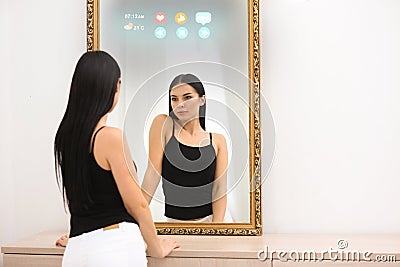 Beautiful woman looking at herself in smart mirror indoors Stock Photo