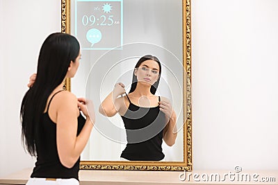 Beautiful woman looking at herself in smart mirror indoors Stock Photo