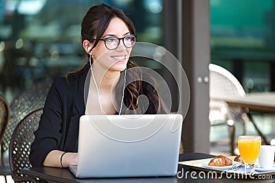 Beautiful young woman looking sideways while working with her laptop in a coffee shop. Stock Photo
