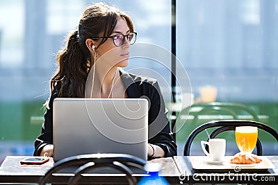 Beautiful young woman looking sideways while working with her laptop in a coffee shop. Stock Photo