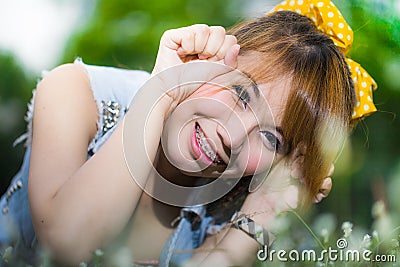 Beautiful young woman lying on grass with flowers Stock Photo