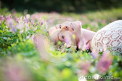 Beautiful young woman lying on grass with spring flowers Stock Photo