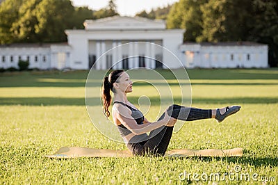 Beautiful young woman lying on a yellow mattress doing pilates or yoga, rolling back beginner exercises Stock Photo