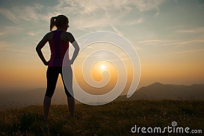 Beautiful young woman observing sunset after running on a mountian Stock Photo