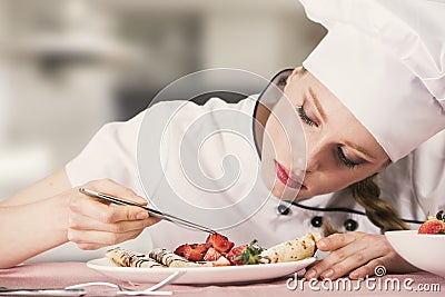 Beautiful young woman pastry chef is food styling a crepe Stock Photo