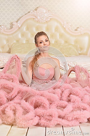 Beautiful young woman in pink dress posing in bedroom Stock Photo