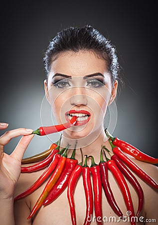 Beautiful young woman portrait with red hot and spicy peppers, fashion model with creative food vegetable make up Stock Photo