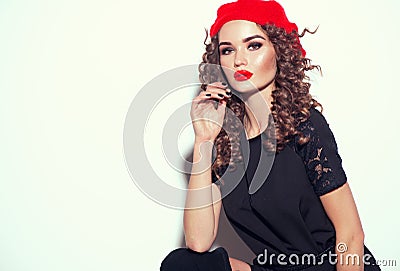 Beautiful young woman posing in studio in black dress and red beret. Beauty model girl portrait. Trendy outfit Stock Photo