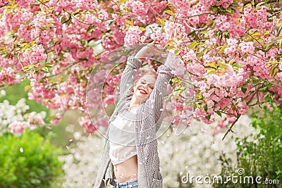 Beautiful young woman with red hair having fun standing in cherry blossom tree Stock Photo