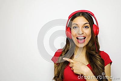 Beautiful young woman with red headphones listening to music smiling and pointing copy space on a white background in a red t-shir Stock Photo