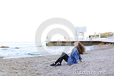 Beautiful young woman relaxes sitting on beach and enjoys view o Stock Photo