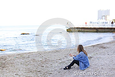 Beautiful young woman relaxes sitting on beach and enjoys view o Stock Photo