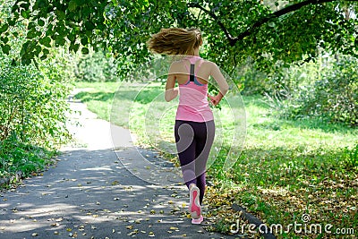 Beautiful young woman running in green park on sunny summer day Stock Photo