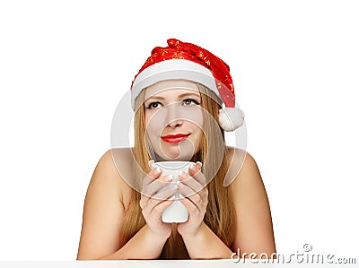 Beautiful young woman in santa claus hat sitting at the table wi Stock Photo