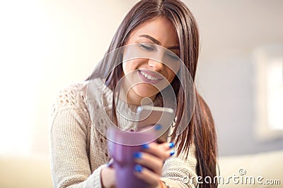 Beautiful young woman sitting on a sofa and send text messages Stock Photo