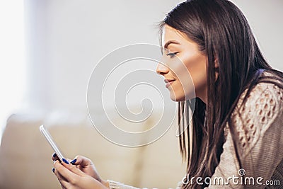 Young woman sitting on a sofa and send text messages Stock Photo