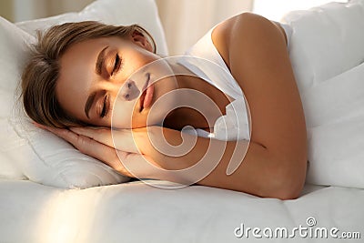 Beautiful young woman sleeping while lying in bed comfortably and blissfully. Sunbeam dawn on her face Stock Photo