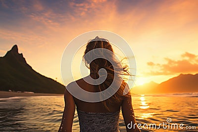 Beautiful young woman standing on the beach and enjoying the sunset, Female surfer rear view in sea at sunset, Oahu, Hawaii, Stock Photo