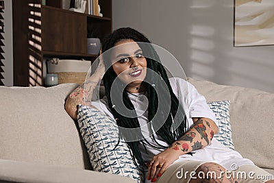 Beautiful young woman with tattoos on body, nose piercing and dreadlocks at home Stock Photo