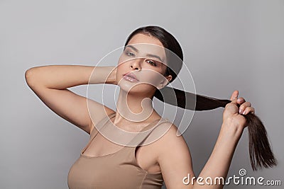 Beautiful young woman touching her ponytail hairstyle with smooth straight hair Stock Photo