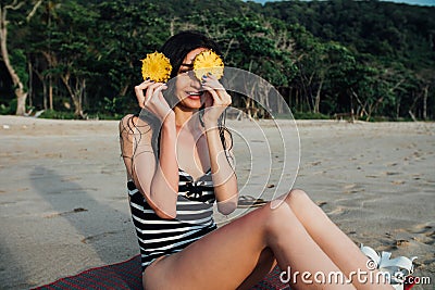 Beautiful young woman tourist In a striped swimsuit holding two ripe pineapple against her eyes. Stock Photo