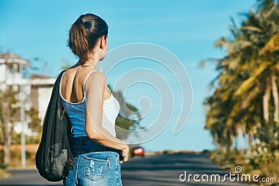 Beautiful young woman traveler with backpack stands near the road. Stock Photo