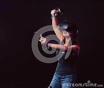 Beautiful young woman with virtual reality headset and joysticks playing video games. Stock Photo