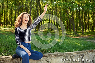 Beautiful young woman waves hand to somebody Stock Photo