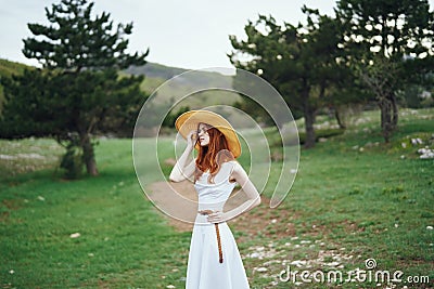 Beautiful young woman in a white dress is standing on a meadow in the mountains Stock Photo