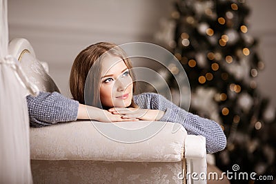 Beautiful young woman in white near the Christmas tree. Beautiful girl celebrates Christmas Stock Photo