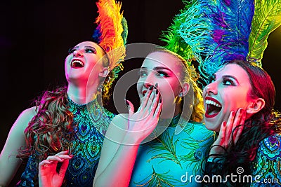 Beautiful young women in carnival and masquerade costume in colorful neon lights on black background Stock Photo