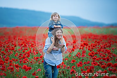 Beautiful young woman with child girl in poppy field. happy family having fun in nature. outdoor portrait in poppies. mother with Stock Photo