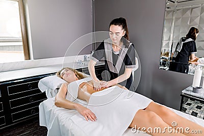 Beautiful young woman having visceral massage in spa center. Young female doctor therapist doing manual massage on Stock Photo