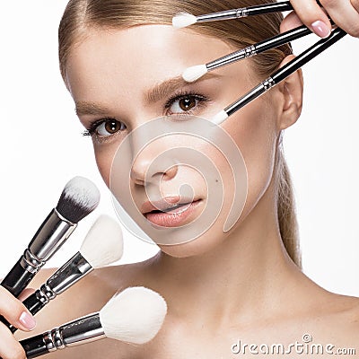 Beautiful young girl with a light natural make-up, brushes for cosmetics and French manicure. Beauty face. Stock Photo