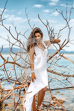 Beautiful ypung stylish woman in white dress on the beach portrait with dry tree Stock Photo