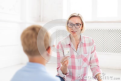 Beautifull mother sits sits in front of her little son and helps him to learn new English words using speacial Stock Photo