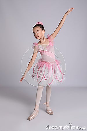 Beautifully dressed little ballerina dancing on grey background Stock Photo