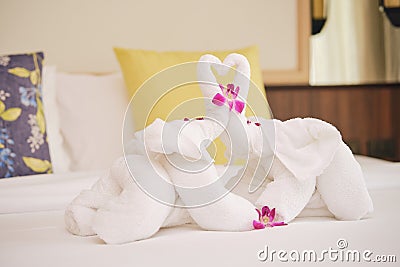 Beautifully folded clean white bath towels set folding fabric into elephant shape with orchid on the bed in Honeymoon suite Stock Photo