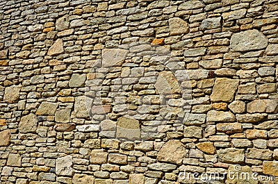 Beautifully folded retaining wall with a granite attic with small joints. brown beige yellow irregular gneiss stone holding a slop Stock Photo